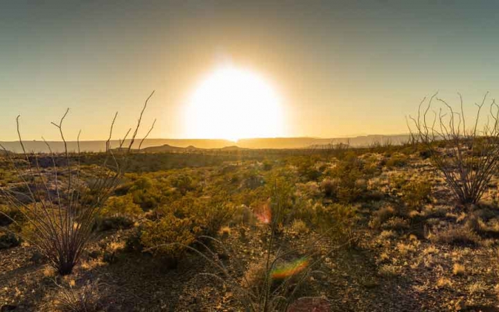 the sun sets behind a desert landscape in texas